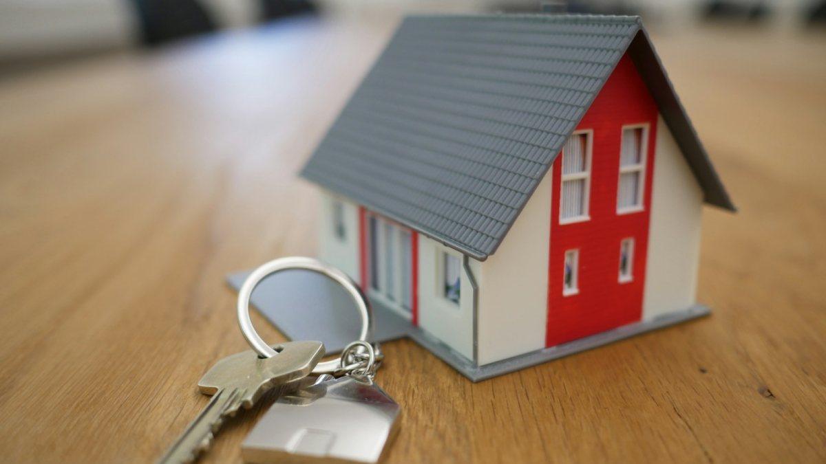 Miniatura de casa ao lado de um molho de chaves sobre a mesa